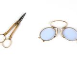 une paire de ciseaux et une paire de lunettes posés sur une surface blanche