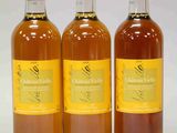 trois bouteilles de vin posées les unes à côté des autres sur une surface blanche