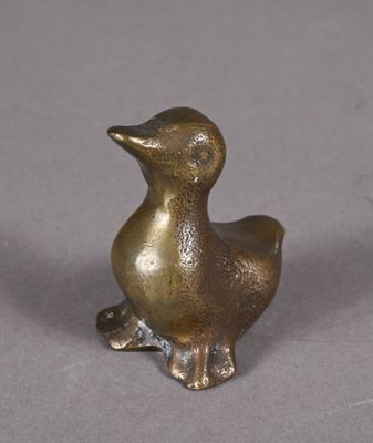 un petit canard en bronze posé sur une table