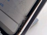 a broken cell phone sitting on a stand with a broken screen