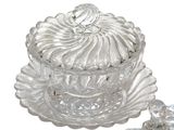a glass bowl with a lid and a spoon on a plate