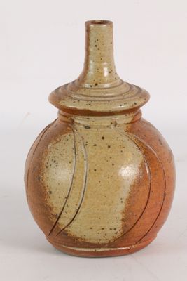un petit vase muni d'un couvercle, posé sur une surface blanche