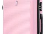 La valise rose repose sur ses roulettes, posée sur une surface blanche.