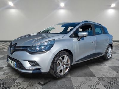 une voiture argentée est garée dans une pièce au sol en damier