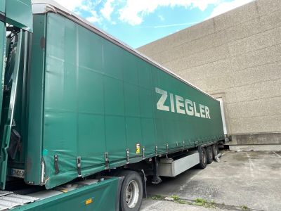 a green semi truck parked in front of a building