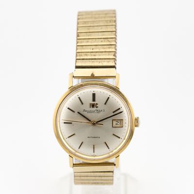 gros plan d'une montre-bracelet en or sur une surface blanche
