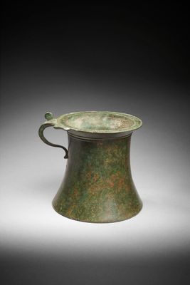 une vieille coupe en bronze munie d'une anse et d'une poignée