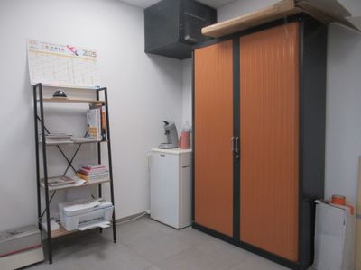 une armoire orange dans un coin de la pièce, à côté d'un réfrigérateur blanc