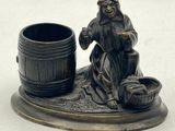a figurine of a woman sitting next to a barrel