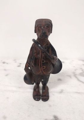 une petite figurine représentant un homme avec un chapeau et un sac
