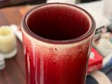 a red vase sitting on a table with candles in the background