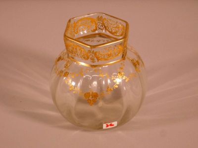a glass vase that has a gold decoration on it