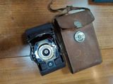 an old camera and a leather case on a wooden table