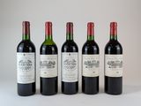 quatre bouteilles de vin sont alignées sur une surface blanche