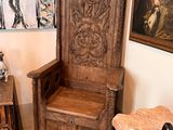 a wooden chair in the corner of a room with a painting on the wall behind it