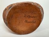 a brown vase with writing on it sitting on a white surface