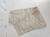 beige pants laying on a bed with white sheets and a white pillow