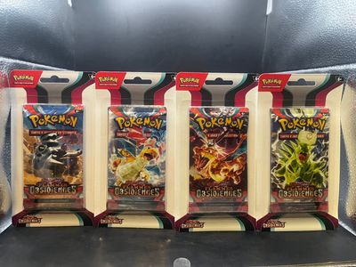 Quatre paquets de cartes à collectionner Pokémon se trouvent dans une vitrine.