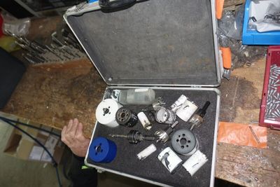 un homme tenant un outil dans un coffret posé sur une table