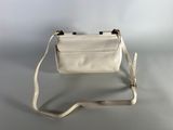 a white purse sitting on top of a table next to a white wall