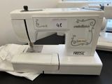 a white sewing machine sitting on a table next to a window