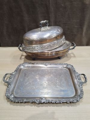 deux plateaux en argent et un plat à couvercle en argent posés sur une table en bois