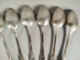 six silver spoons are lined up on a white surface