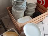 many plates and bowls in a wooden box on the floor