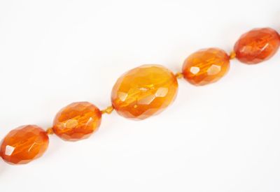 un gros plan sur un collier de perles de verre orange posé sur une surface blanche