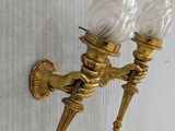 brass wall sconce with two white glass lamps mounted on a wall
