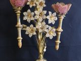an antique brass candelier with pink flowers on a black background