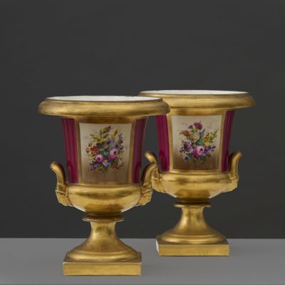 pair of gold vases with flowers on them sitting on top of a table