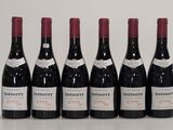 six bouteilles de vin sont alignées sur une table