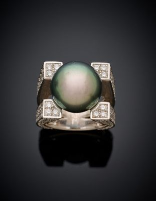 a black pearl and diamond ring on a black surface