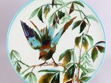 une assiette sur laquelle est peint un oiseau perché sur une branche d'arbre