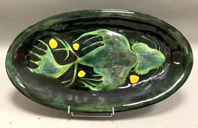 une assiette verte avec une grenouille dessus, posée sur une table