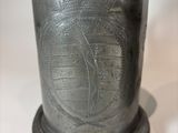 a silver cup with a handle on a white table