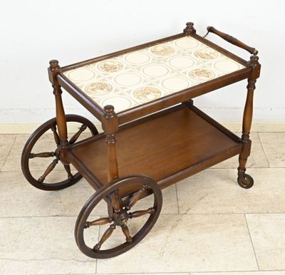 une petite charrette en bois avec un plateau en tuiles montée sur roues