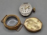 two gold and silver pocket watches sitting on top of a table