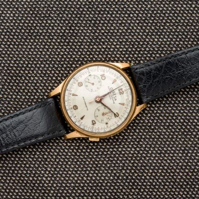 un gros plan d'une montre en or avec un bracelet en cuir noir
