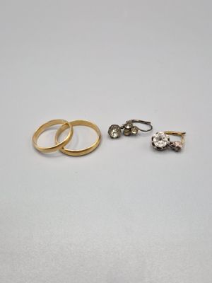 deux alliances en or et une bague en diamant posées sur une surface blanche