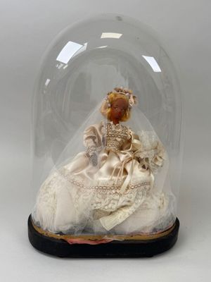 une figurine représentant une femme en robe de mariée, placée sous un dôme en verre