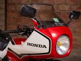 a red and white motorcycle parked in front of a brick wall