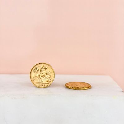 a gold coin sitting on top of a white box next to a pink wall