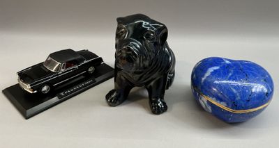 une figurine de chien assise à côté d'un livre et d'une balle bleue