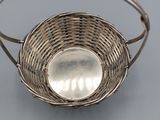 a silver basket with a spoon in it on a table