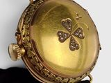 a close up of a gold pocket watch on a black strap
