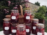 Plusieurs pots de confiture sont posés sur une table devant un panier de fleurs