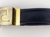 ceinture en cuir noir avec une boucle dorée sur fond blanc