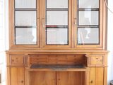 a large wooden cabinet with glass doors and a desk in front of it